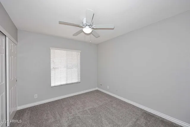 an empty room with a window and a fan