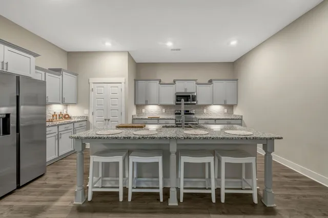 a kitchen with stainless steel appliances granite countertop a table chairs stove refrigerator and microwave