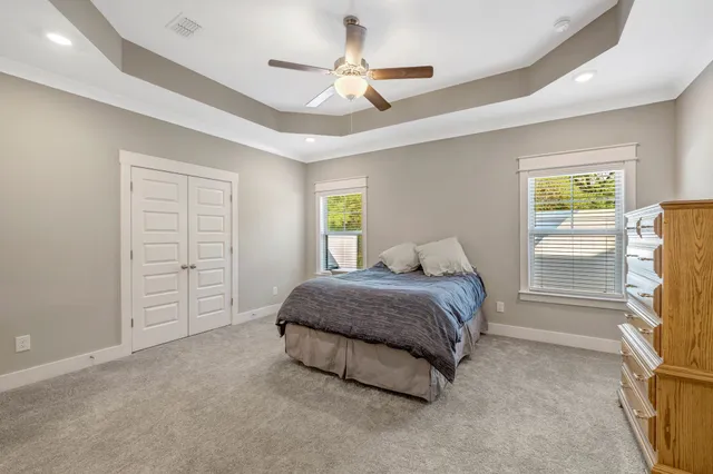 a spacious bedroom with a bed a dresser and a chandelier