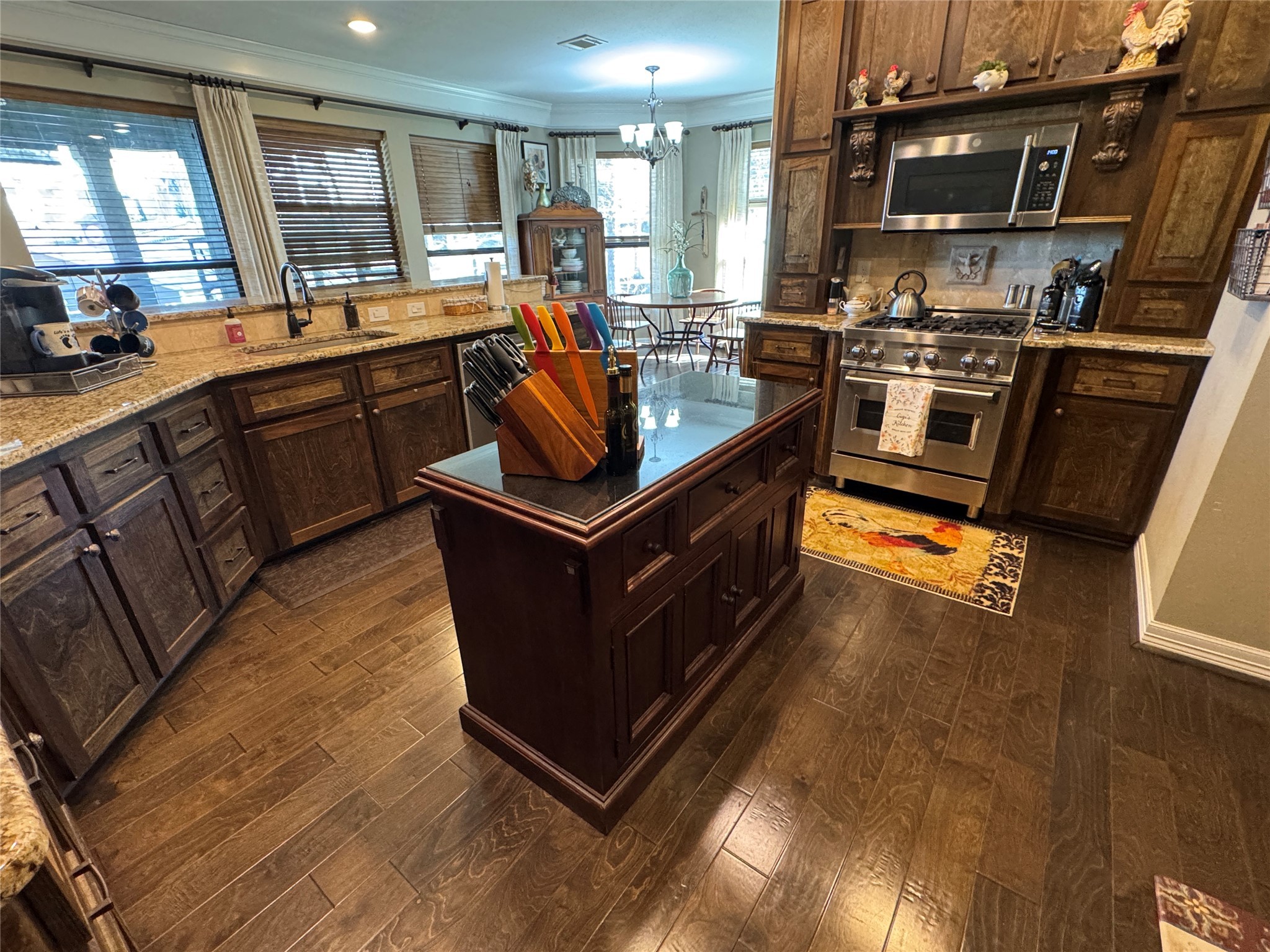 200 Harbor Run Drive Coldspring, TX 77331 - Photo 12 of 50 This kitchen features rich dark wood cabinetry, granite countertops, and a central island with ample storage. Stainless steel appliances add a modern touch, while large windows provide natural light, creating a warm and inviting atmosphere.