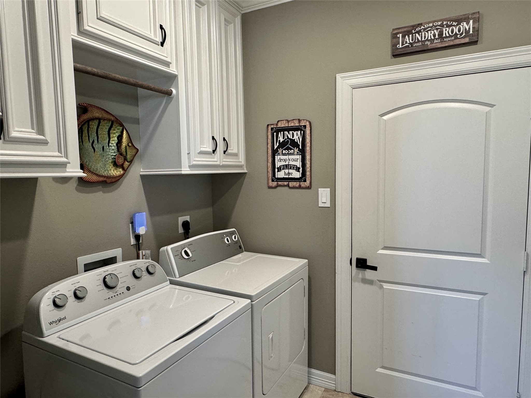 200 Harbor Run Drive Coldspring, TX 77331 - Photo 37 of 50 A well-designed laundry room with white cabinetry for both sides. This room offers two areas to hang your short and long apparel right from the dryer. The door in the photo takes you directly into the oversized garage!