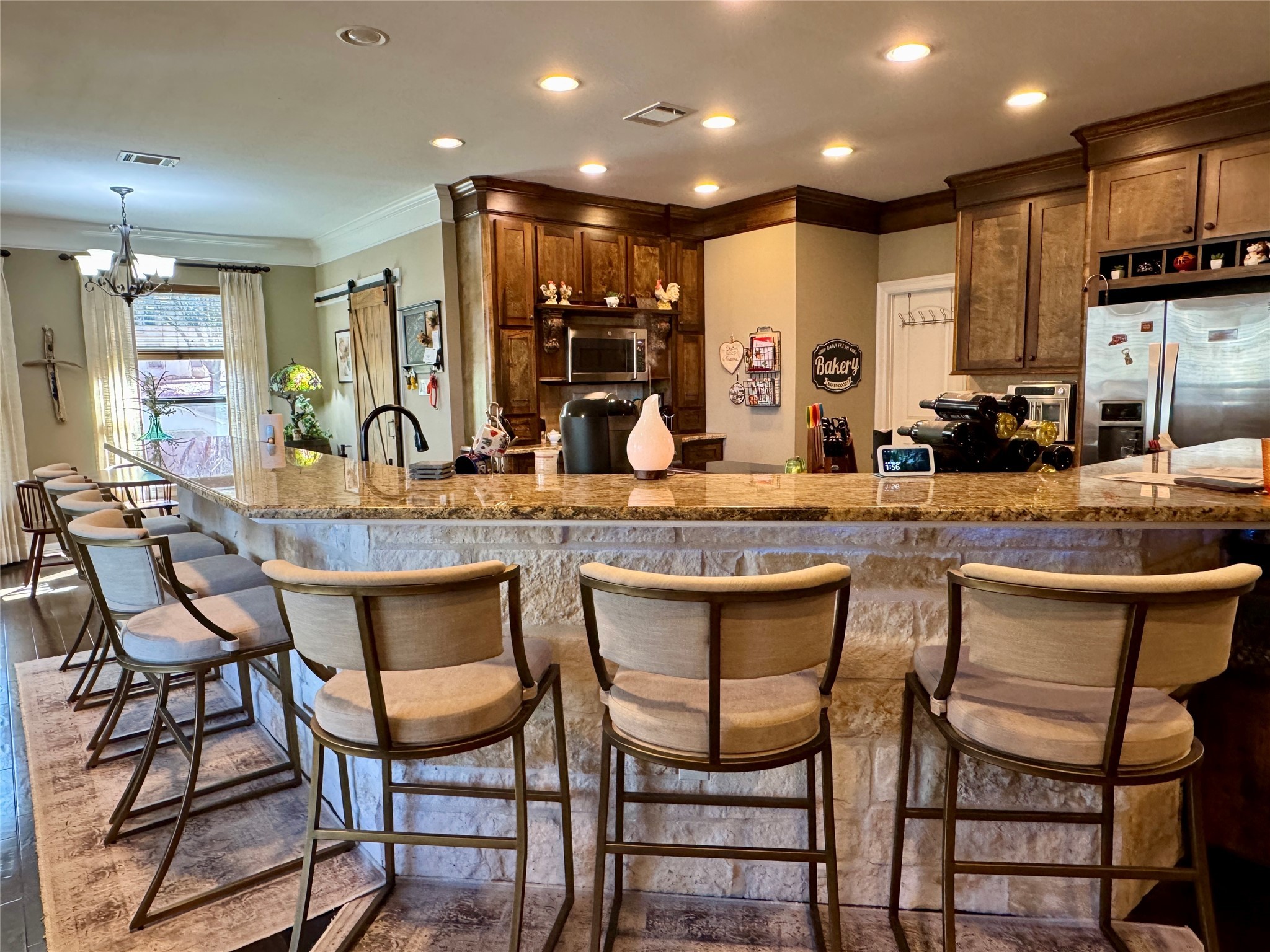 200 Harbor Run Drive Coldspring, TX 77331 - Photo 10 of 50 This inviting kitchen features a large stone island with granite countertops, complemented by wooden cabinetry and stainless steel appliances. The space is well-lit with recessed lighting, and the row of barstools highlight just how ample the seating space is. This home is perfect for entertaining.