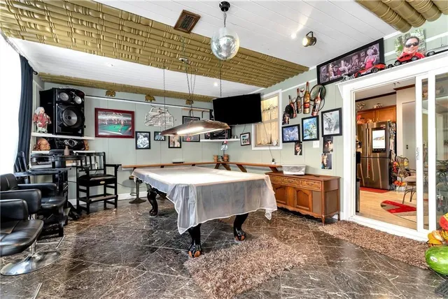 a living room with stainless steel appliances furniture a rug kitchen view and a table