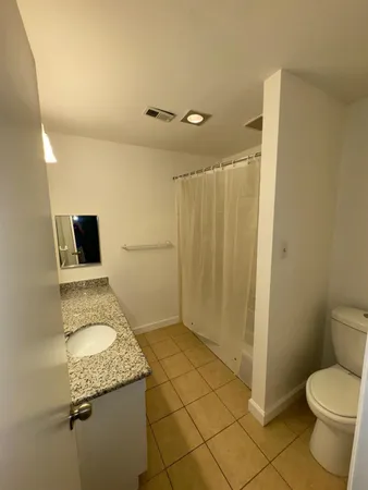 a bathroom with a granite countertop sink toilet and shower