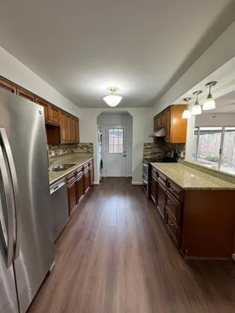 a large kitchen with stainless steel appliances granite countertop a stove a sink dishwasher and a refrigerator