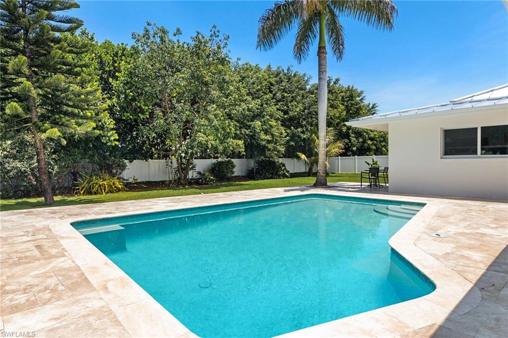 2001 Alamanda Drive Naples, FL 34102 - Photo 25 of 32 a view of a swimming pool with a chair and palm trees