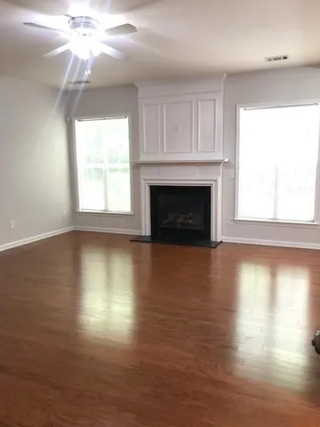 an empty room with wooden floor fireplace and windows