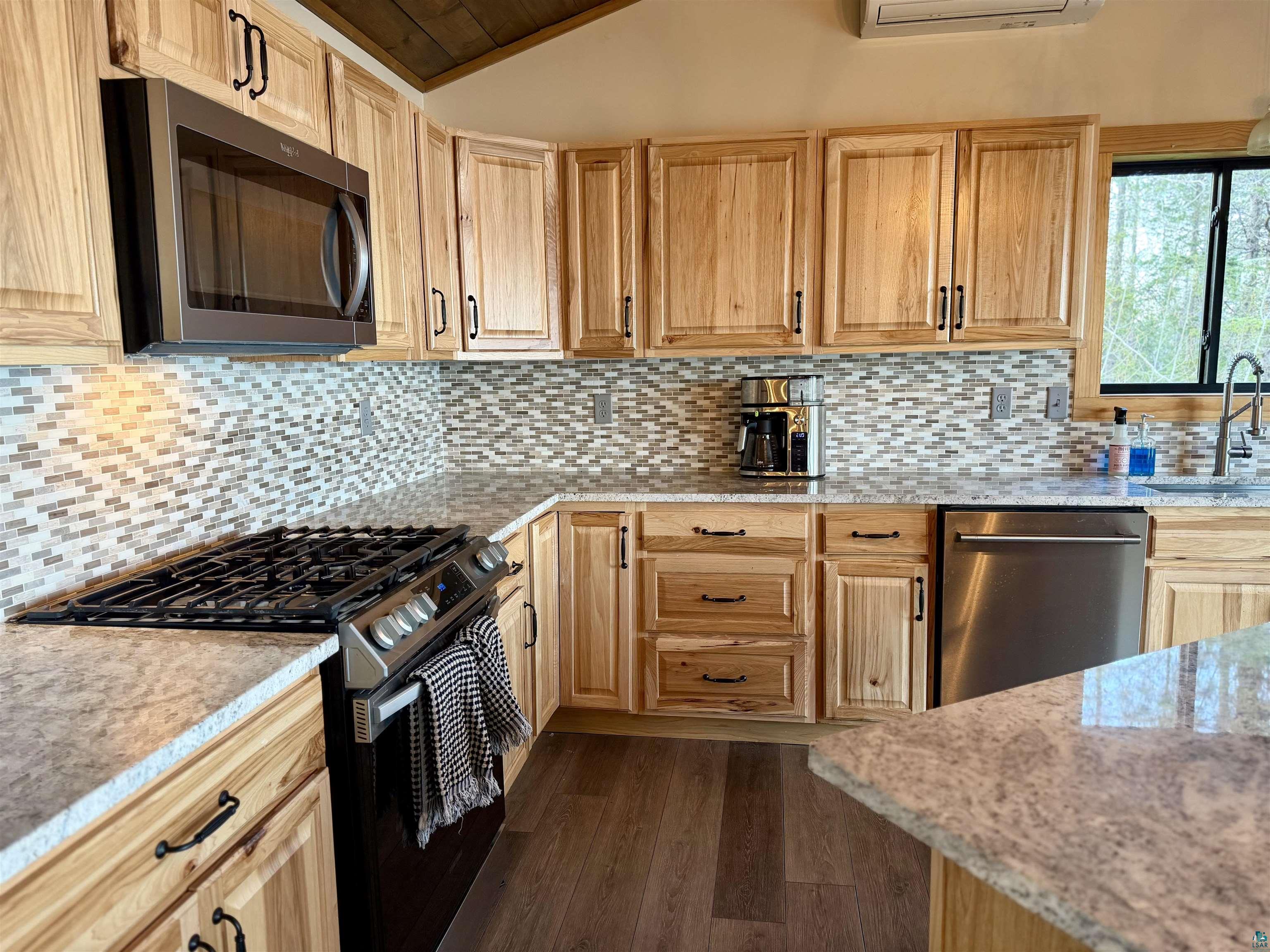 5274 Marble Lake Road Two Harbors, MN 55616 - Photo 20 of 79 Kitchen featuring wood-finish cabinetry, light-toned countertops, a mosaic tile backsplash, and stainless steel appliances including a microwave, gas range, and dishwasher