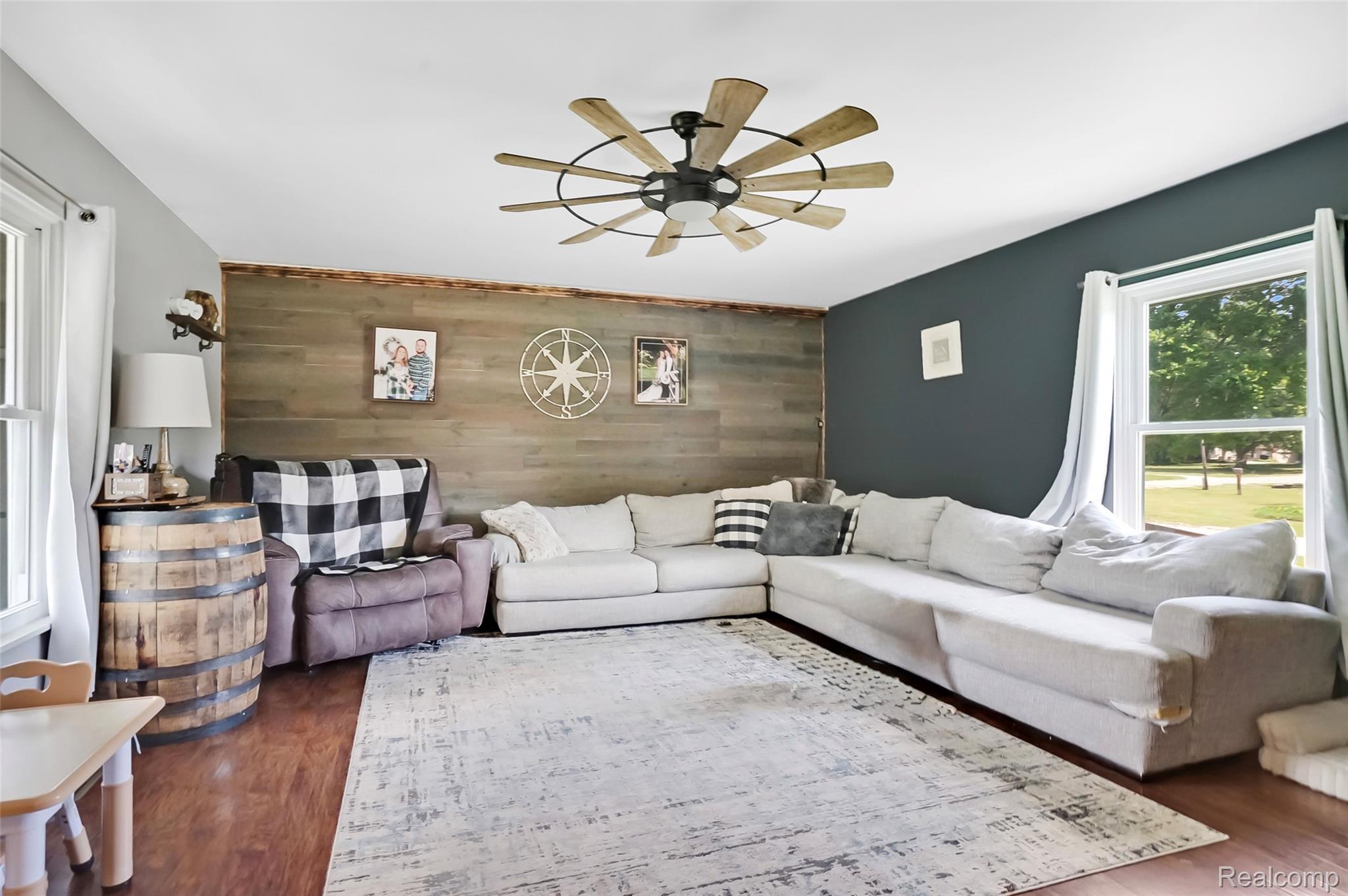 6050 Brophy Road Howell, MI 48855 - Photo 4 of 27 Spacious living area featuring wood-finish flooring, a decorative accent wall, and a large window providing natural light