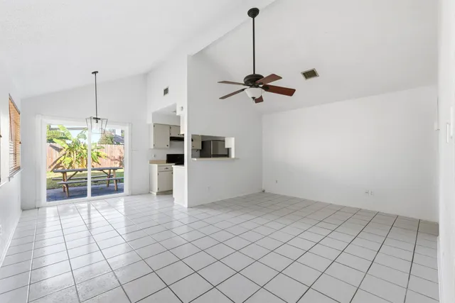 a view of an empty room and chandelier fan