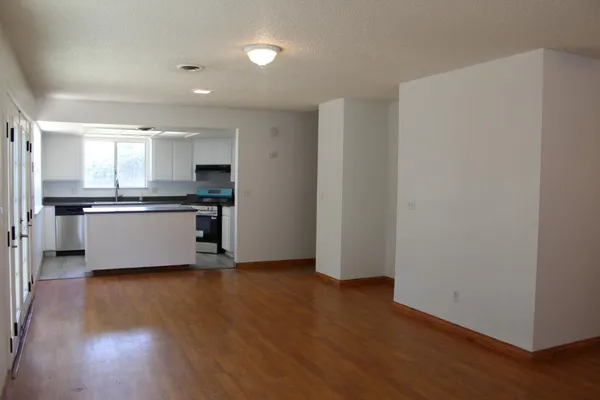 an empty room with wooden floor fireplace and windows