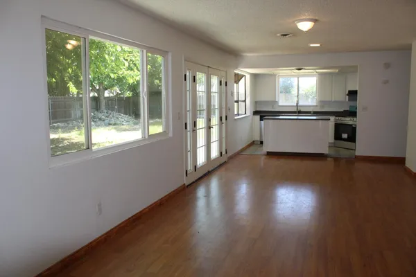 a view of an empty room with wooden floor and a window