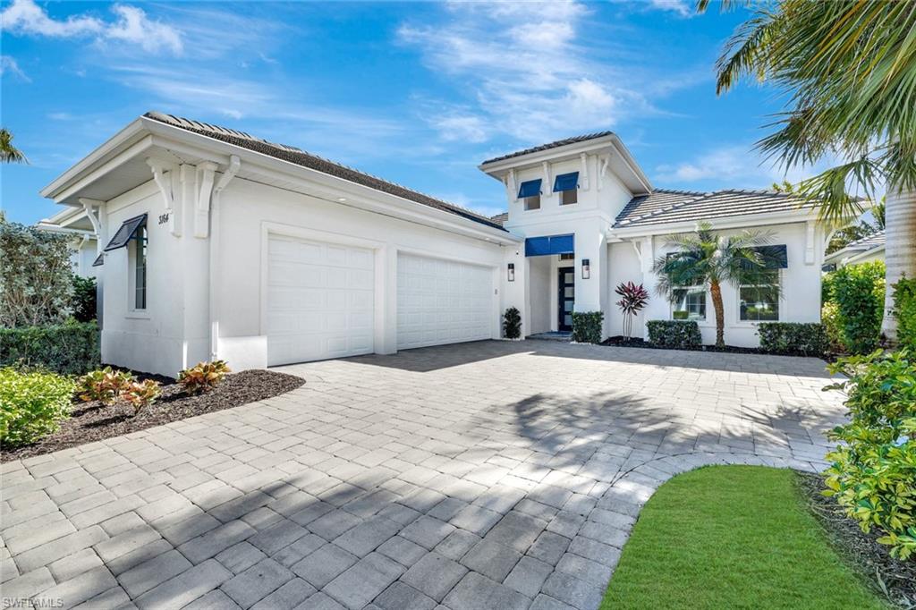 View of front of home with stucco siding, decorative driveway, and a garage