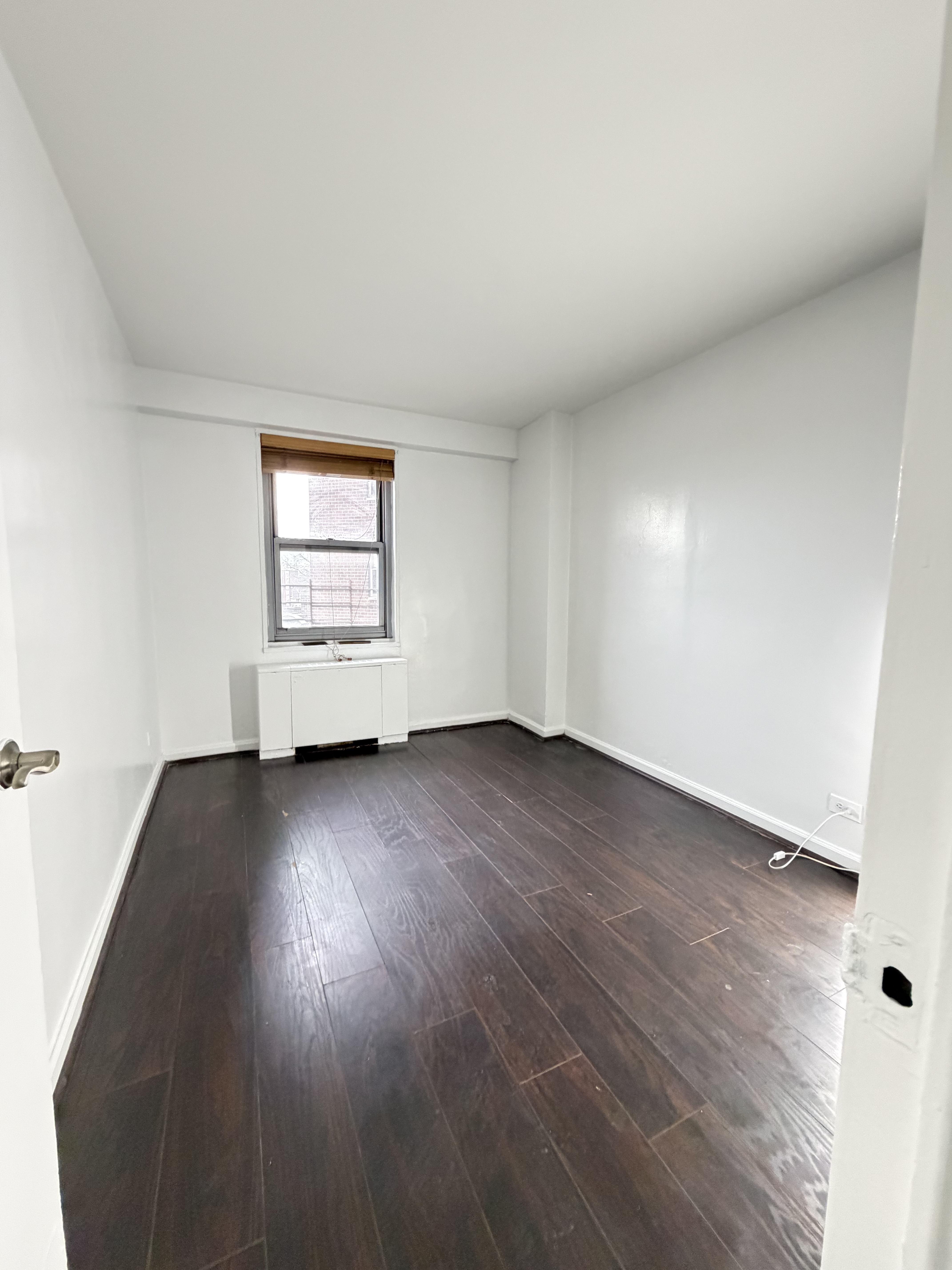 85-15 Main Street, Unit 2R Queens, NY 11435 - Photo 12 of 15 an empty room with wooden floor and windows