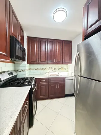 a kitchen with granite countertop a refrigerator a stove a sink and cabinets