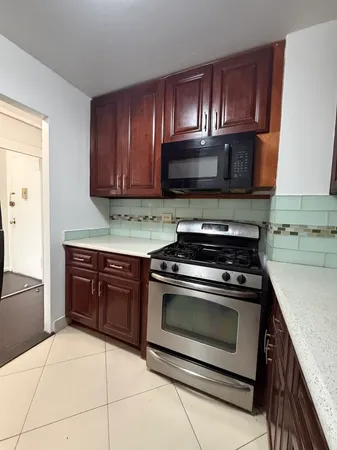 a kitchen with granite countertop wooden cabinets stainless steel appliances and a counter space