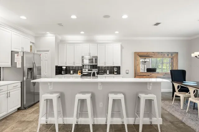 a kitchen with white cabinets and chairs