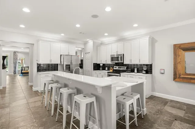 a large white dining space with stainless steel appliances kitchen island a table and chairs in it