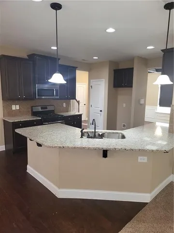 a view of a kitchen with kitchen island a sink wooden floor and a counter top space