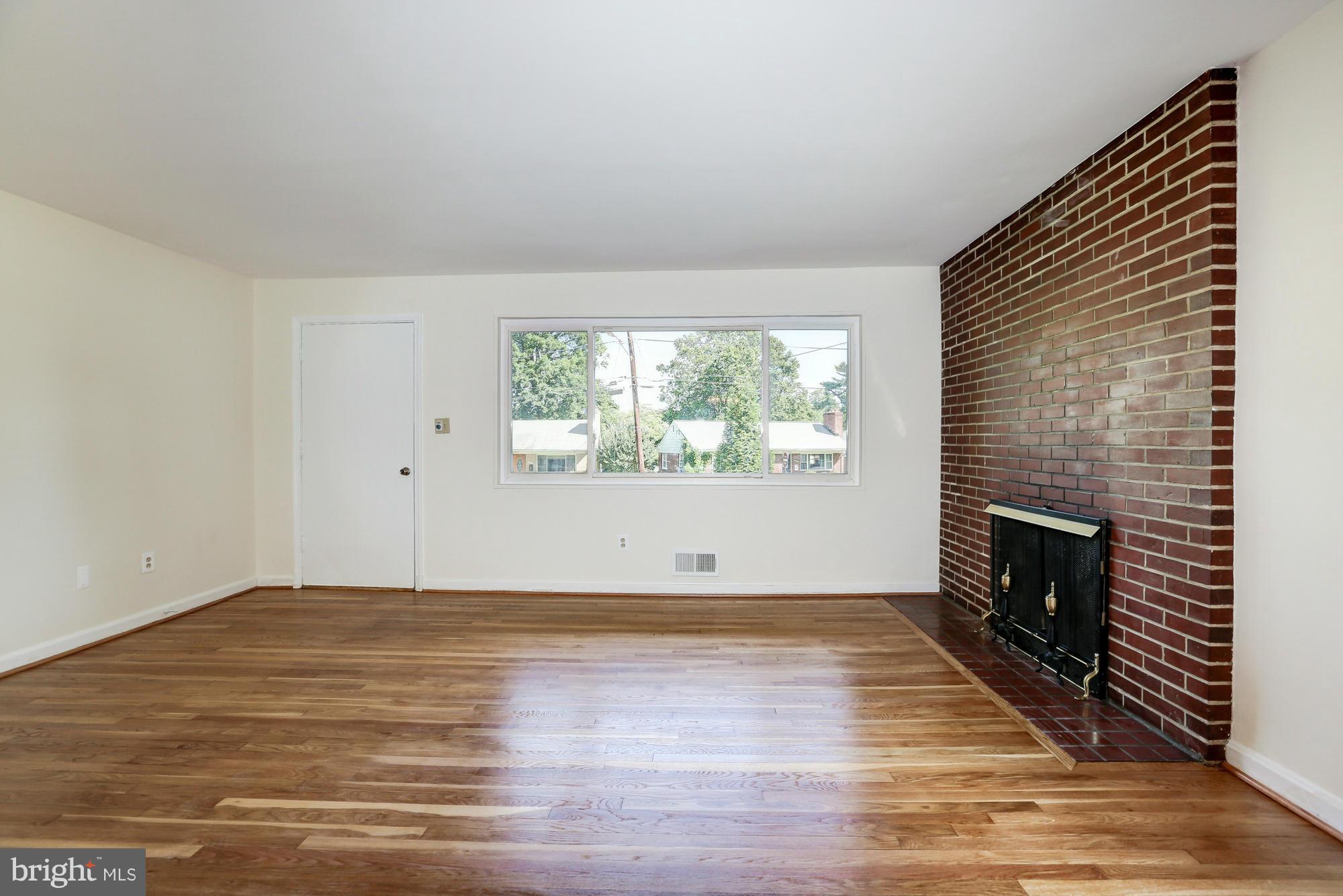 10123 Renfrew Road Silver Spring, MD 20901 - Photo 4 of 18 an empty room with wooden floor and fireplace