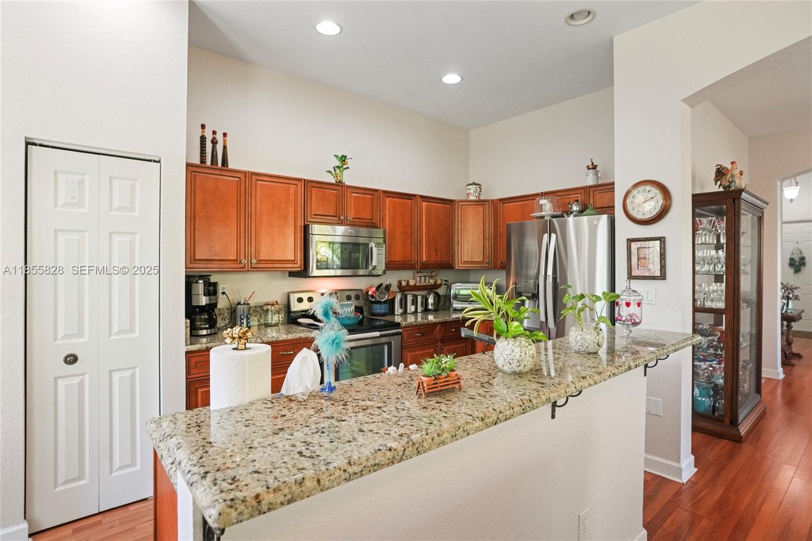 9506 Southwest 220th Lane Cutler Bay, FL 33190 - Photo 14 of 51 a kitchen with stainless steel appliances granite countertop a refrigerator a stove and a sink with wooden floor