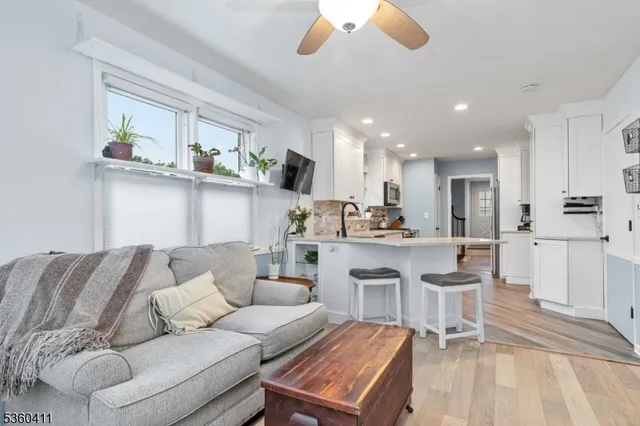 a living room with a couches and kitchen view with wooden floor