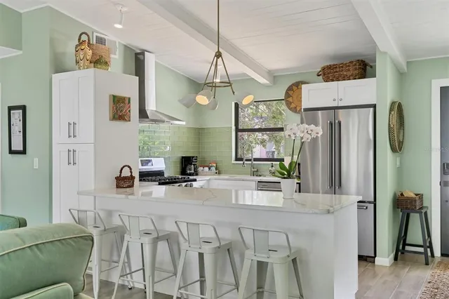 a kitchen with stainless steel appliances a sink a refrigerator a kitchen island and a stove