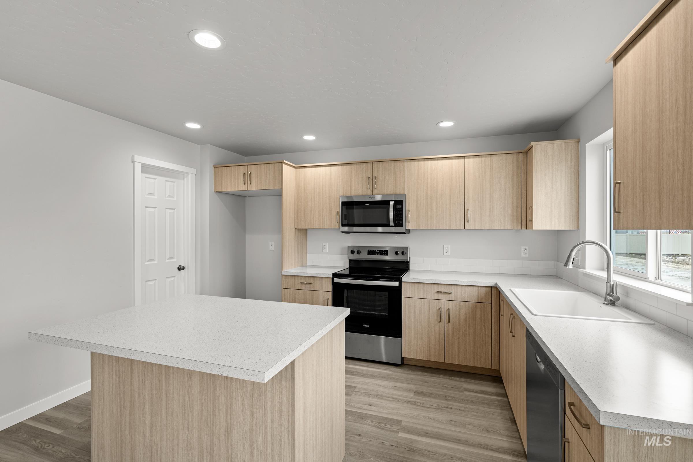 14056 Shiny Spruce Street Caldwell, ID 83607 - Photo 6 of 25 Kitchen featuring light wood-finish cabinetry, white solid surface countertops, and stainless steel appliances