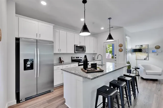 a kitchen with kitchen island granite countertop a sink appliances cabinets and a counter top space