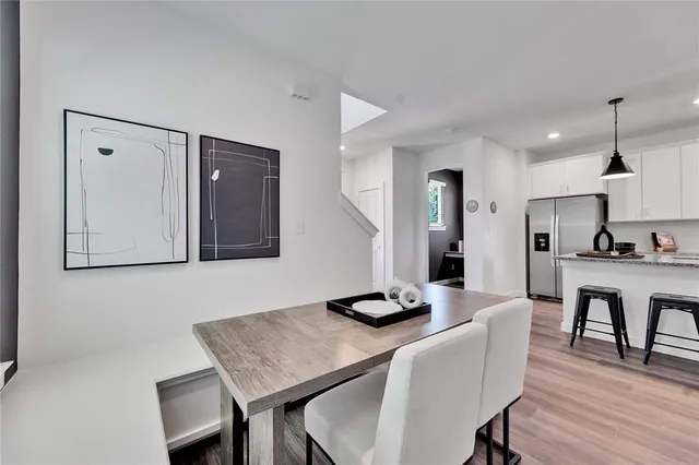 a kitchen with stainless steel appliances granite countertop a stove a sink a microwave a refrigerator and white cabinets with wooden floor