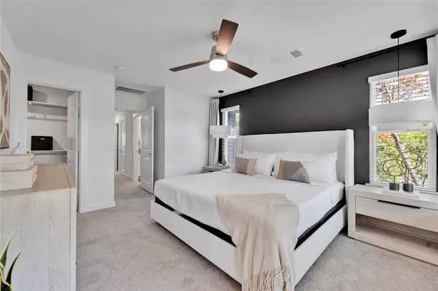 a bedroom with a large bed and a chandelier fan