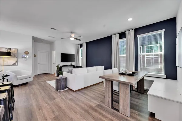 a living room with furniture a flat screen tv and a wooden floor