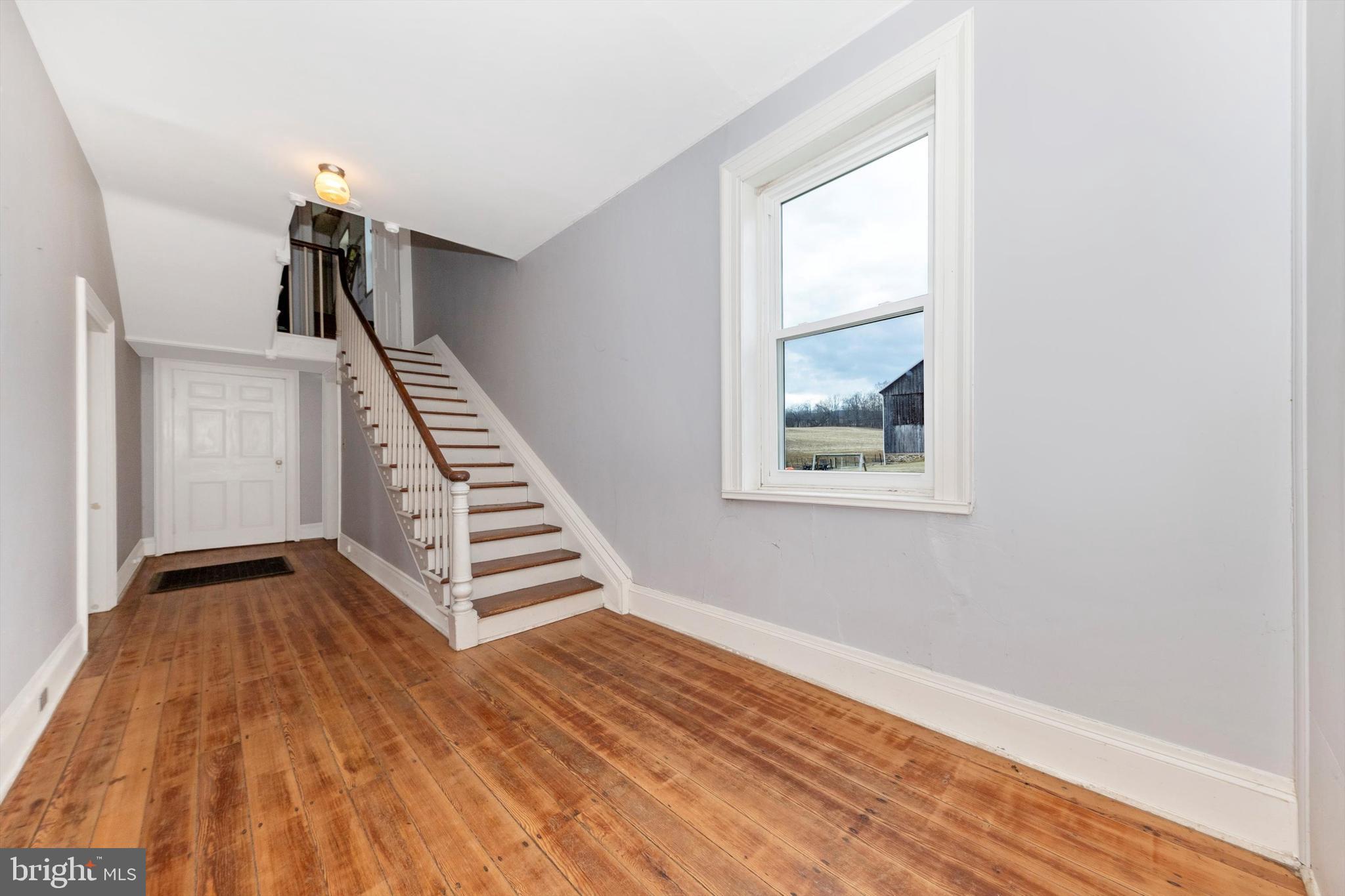 2820 Milt Summers Road Middletown, MD 21769 - Photo 25 of 88 a view of an empty room with wooden floor stairs and a window