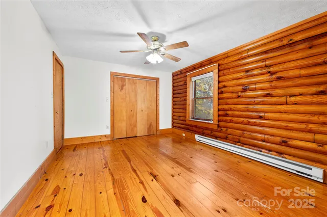 a view of an empty room with window and wooden floor