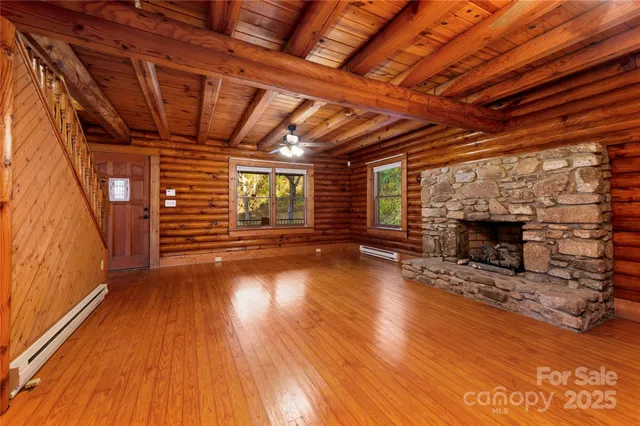 a view of an empty room with wooden floor fireplace and a window