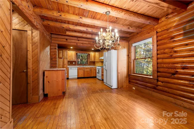 a view of a hallway with wooden floor and a kitchen