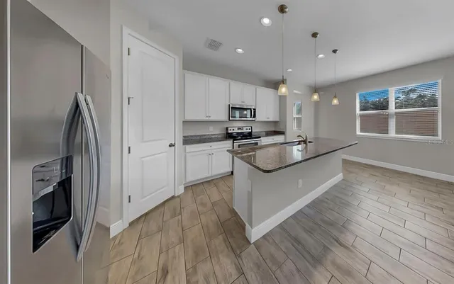 a view of a hallway with wooden floor and a kitchen