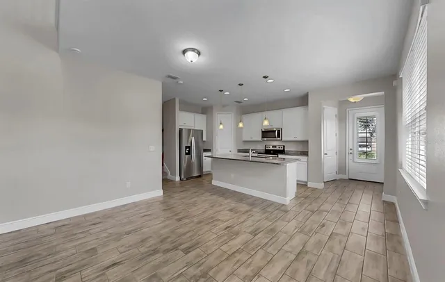 a kitchen with stainless steel appliances granite countertop a refrigerator a stove top oven a sink and dishwasher with wooden floor