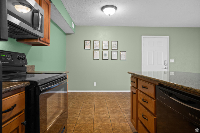 2095 South Main Street, Unit 13 Bountiful, UT 84010 - Photo 9 of 45 Kitchen with black appliances, a textured ceiling, wood finish cabinets, dark stone counters, and dark tile patterned floors