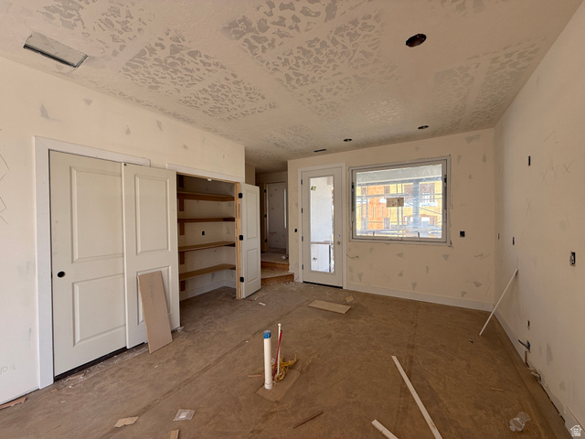 11021 South Freestone Road, Unit 121 South Jordan, UT 84009 - Photo 3 of 31 Spacious interior with uninstalled wood-finish flooring, featuring a large window, a glass-paned exterior door, and a built-in closet with shelves