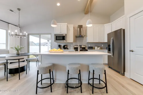 a kitchen with stainless steel appliances a table chairs refrigerator and microwave