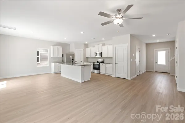 a view of an empty room with kitchen and kitchen view