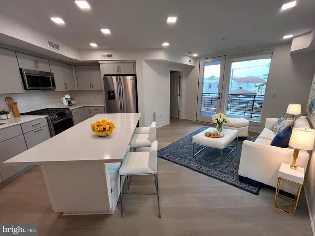 a outdoor kitchen with stainless steel appliances kitchen island granite countertop a stove a sink a table and chairs