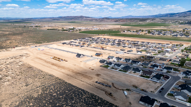 4978 North 75 East Enoch, UT 84721 - Photo 60 of 60 Expansive residential development featuring multiple completed homes, new construction sites, paved roads, and extensive undeveloped land with mountainous backdrops