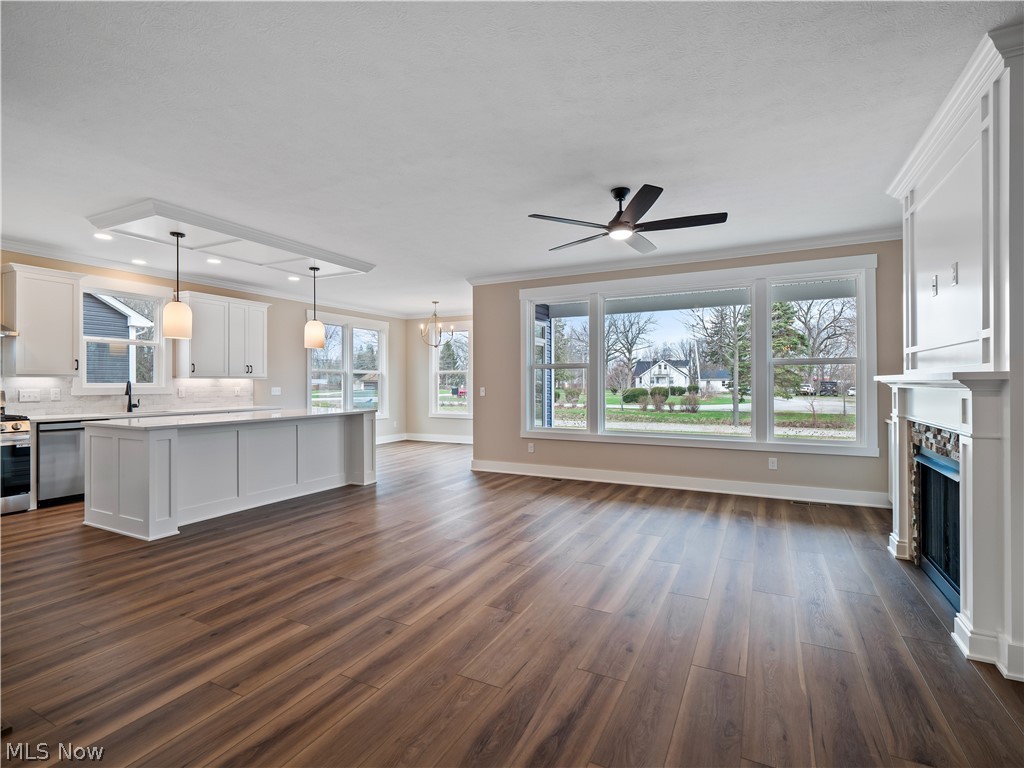 34270 Brookside Lane North Ridgeville, OH 44039 - Photo 14 of 50 Unfurnished living room with ceiling fan, ornamental molding, a fireplace, hanging lights, and dark wood-style flooring