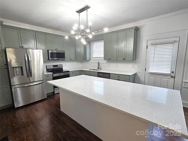 a large white kitchen with a stove a refrigerator and a sink