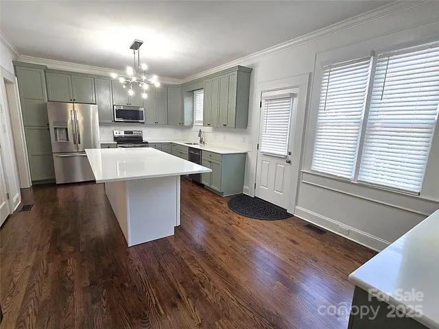 a large kitchen with a wooden floor and stainless steel appliances