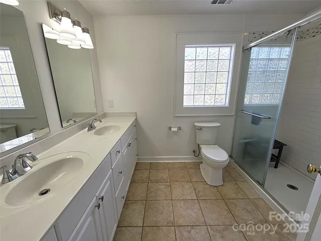 a spacious bathroom with a double vanity sink a toilet and a mirror