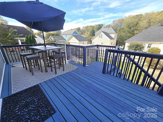 a view of a chairs and table on the wooden roof deck