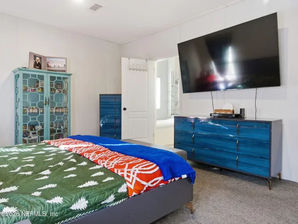 a bedroom with a bed flat screen tv and a window